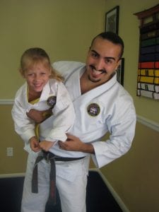 A Jujitsu Instructor carrying his young child student